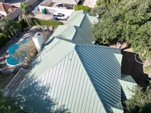 Aerial view of a green standing seam metal roof beside a backyard pool