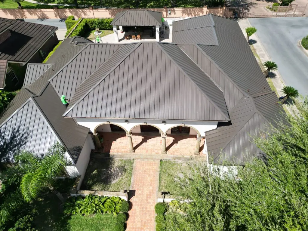 Aerial view of a brown standing seam metal roof above an arched front entry
