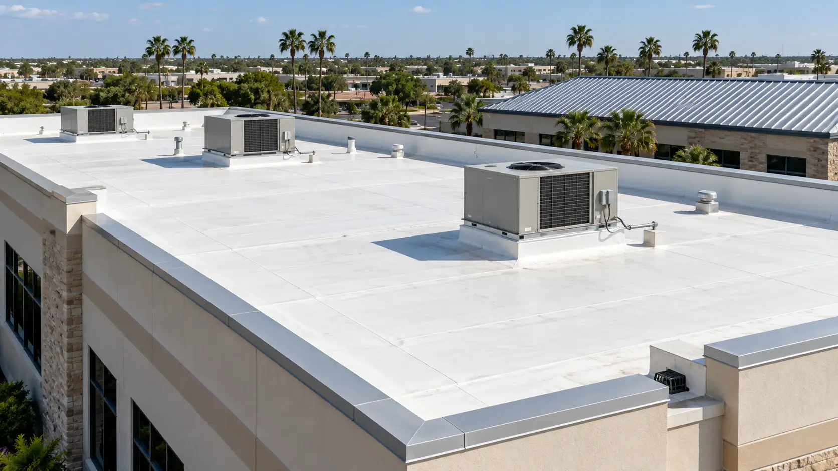 White commercial TPO roof with HVAC units and a neighboring standing-seam metal roof