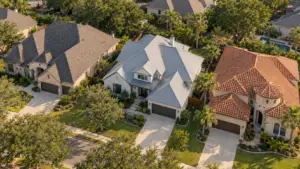 Aerial illustration of neighboring homes with asphalt shingle, standing-seam metal, and clay tile roofs