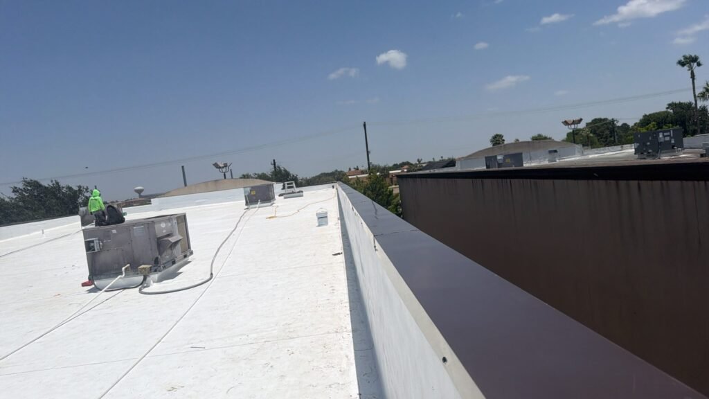 White commercial membrane roof with rooftop equipment and a parapet along the roof edge.