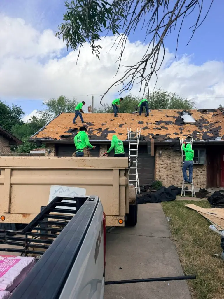 Marva Roofing crew removing old roofing from a home, with exposed wood decking and a debris trailer below.
