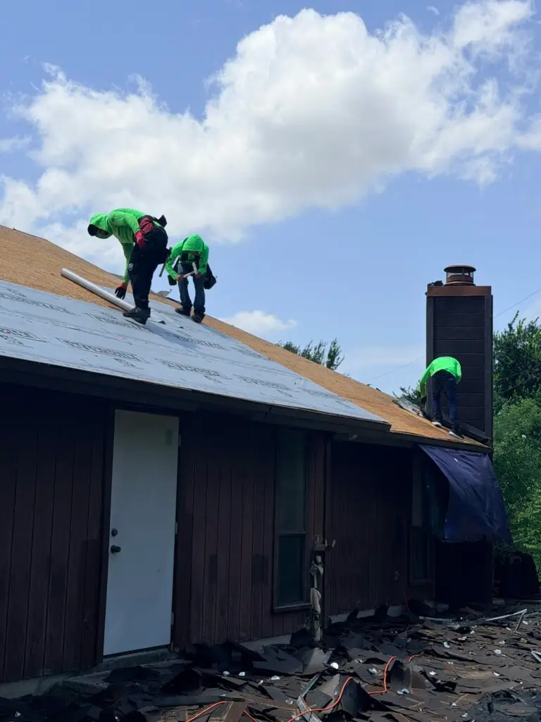 Marva Roofing crew working on exposed roof decking and underlayment beside a chimney.